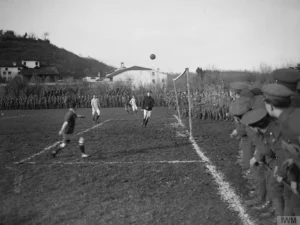 Soldados europeus participam de uma partida de futebol improvisada durante a Trégua de Natal de 1914, enquanto outros observam ao redor, em um raro momento de confraternização na Primeira Guerra Mundial.
